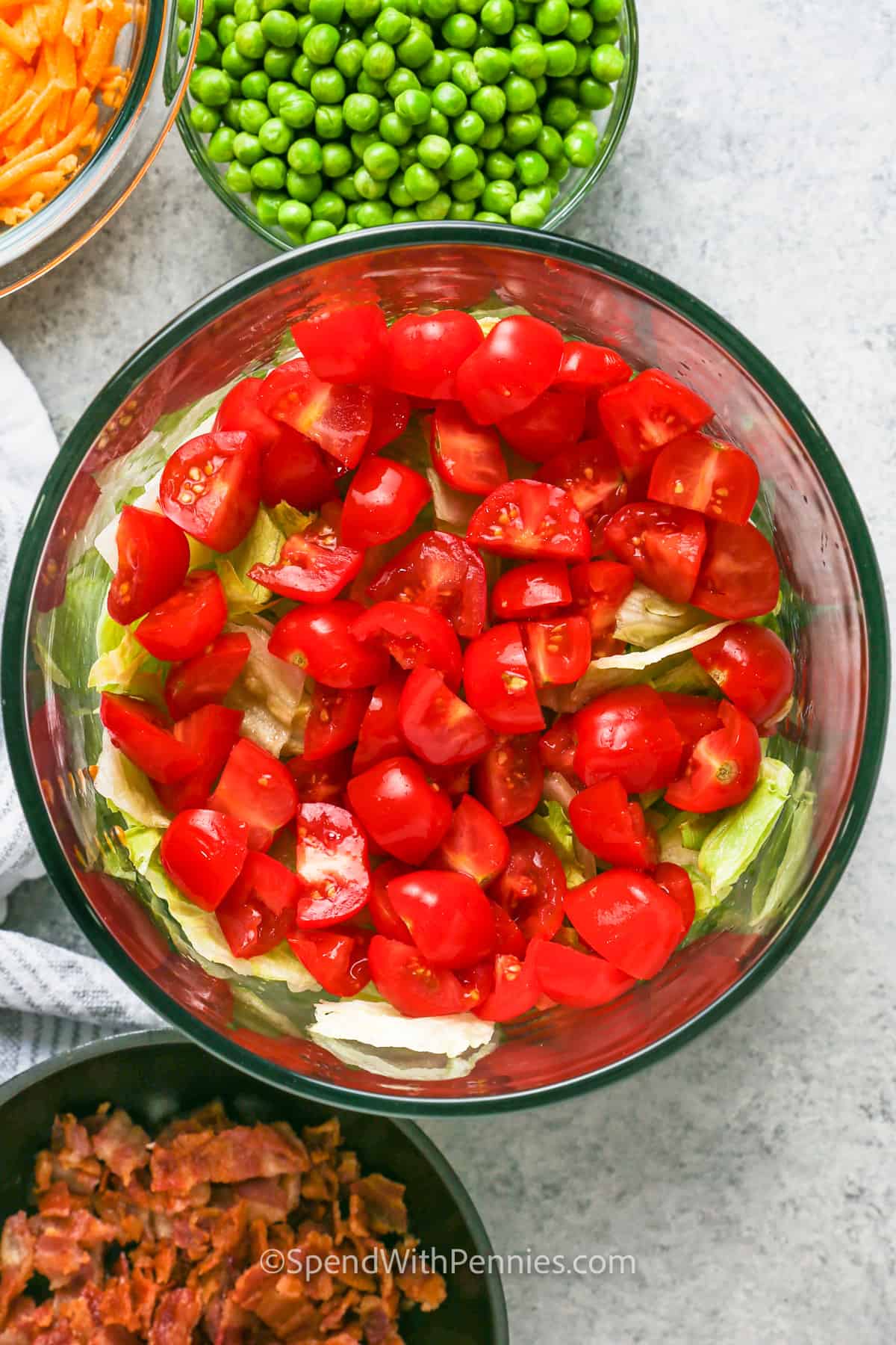 adding tomatoes to bowls to make 7 Layer Salad