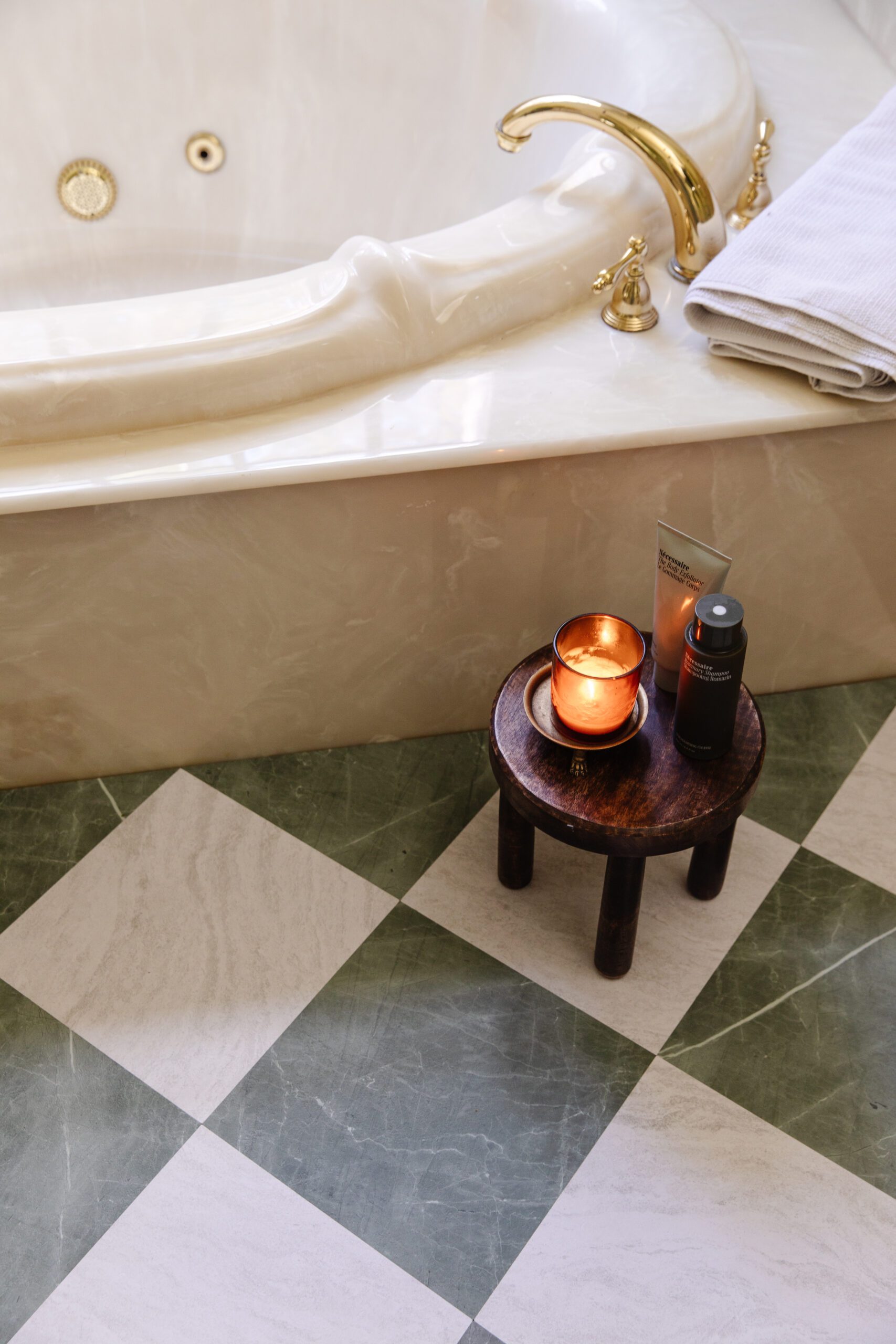 Close-up of a primary bathroom floor next to a tub featuring floor tiles in green & white marble checkerboard