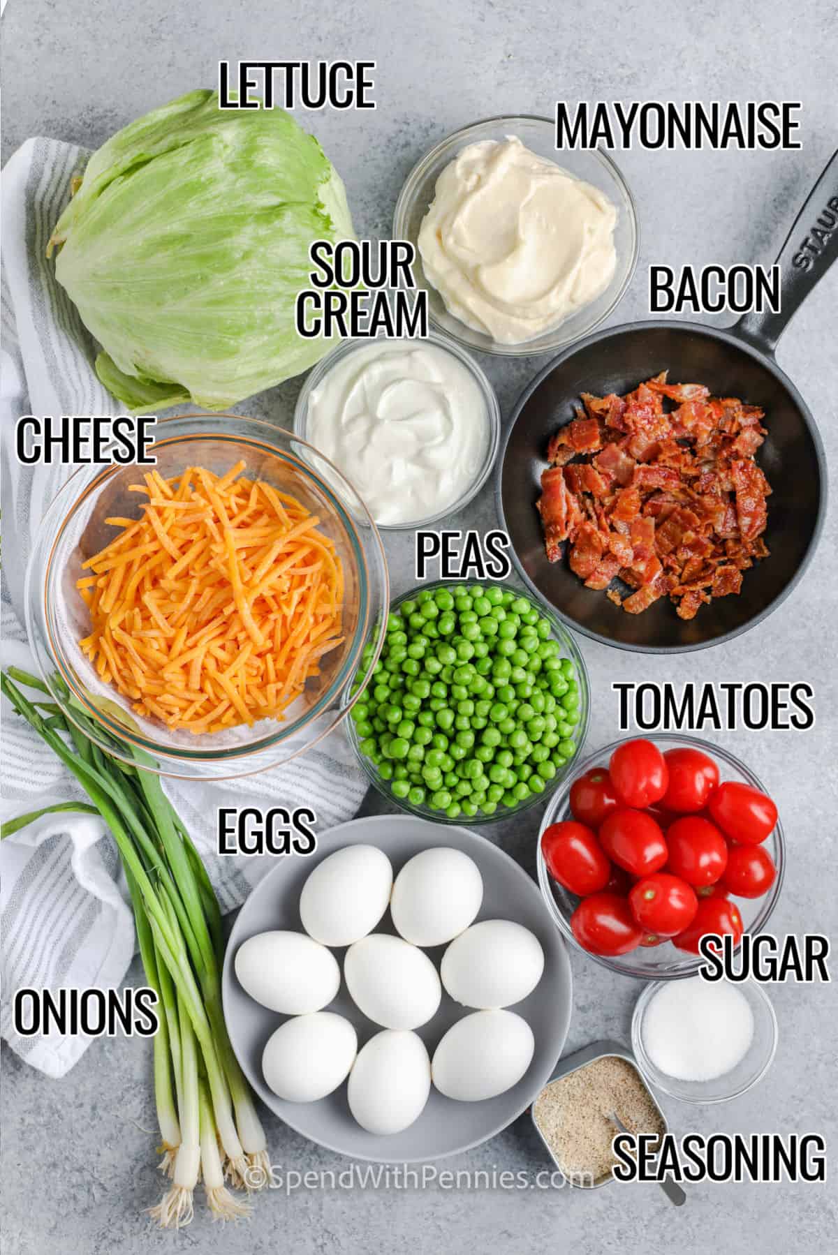 lettuce, mayonnaise, sour cream, bacon, cheese, peas, tomatoes, sugar, hard-boiled eggs, onions, and seasonings with labels to make 7 Layer Salad