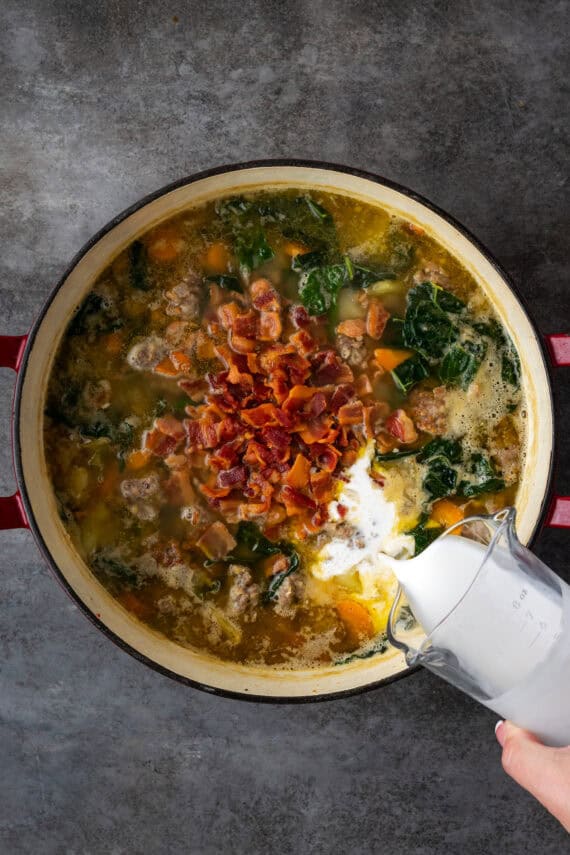 Heavy cream and bacon being added to a pot of Zuppa Toscana.