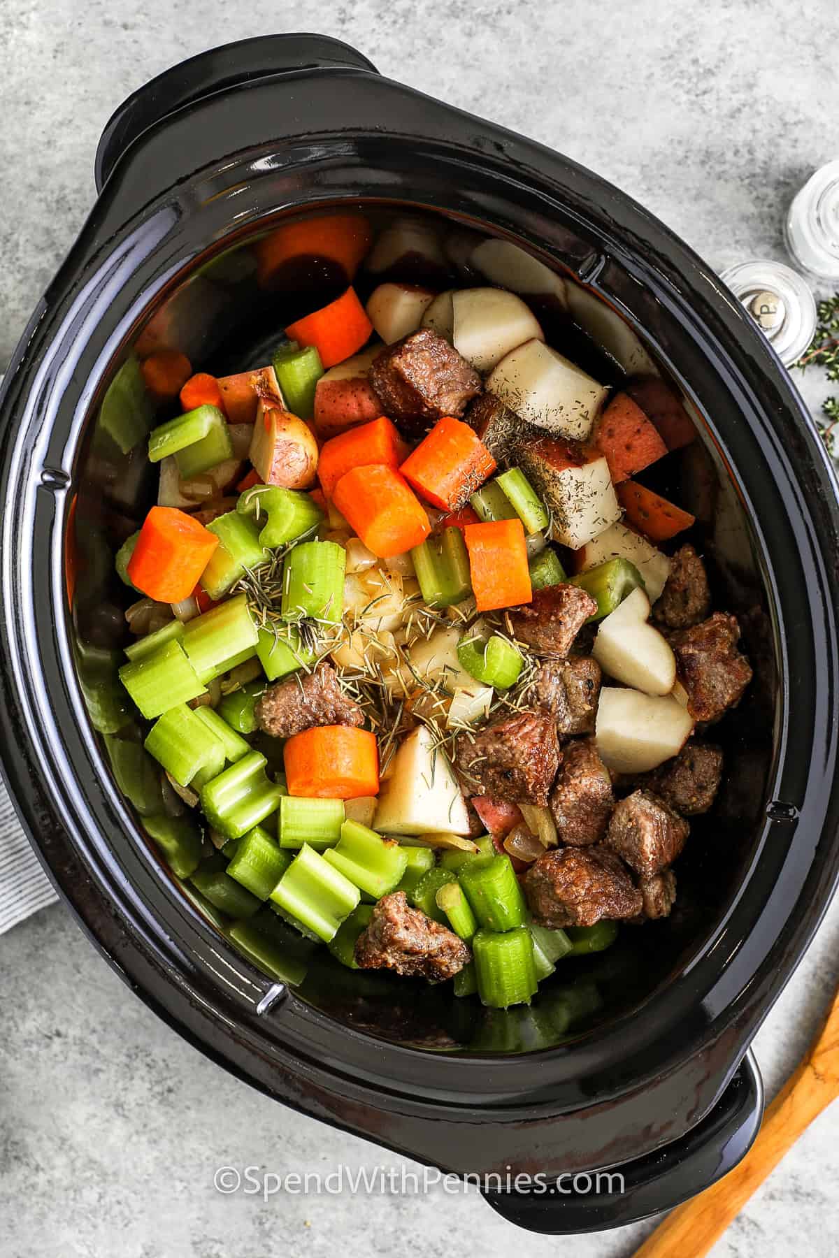 Crockpot beef stew is the coziest dinner ever! Tender beef, hearty potatoes, and veggies slow-cooked in a savory broth make every bite irresistible. With simple ingredients and a touch of seasoning, this one-pot wonder is perfect for any night of the week. Serve it with crusty bread for a meal that warms you from the inside out. Plus, leftovers freeze beautifully for easy meals later! #spendwithpennies adding ingredients to pot to make Crock Pot Beef Stew