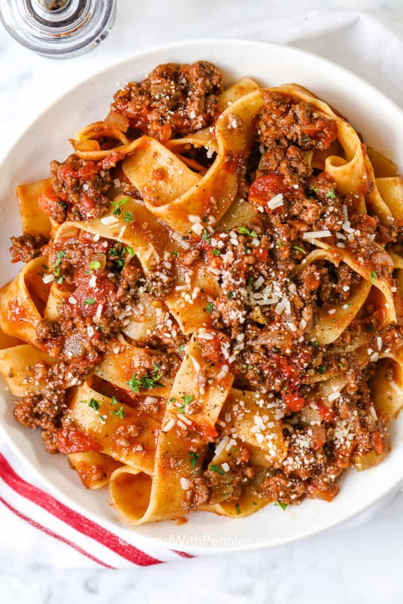 a plate of bolognese pappardelle topped with parmesan cheese