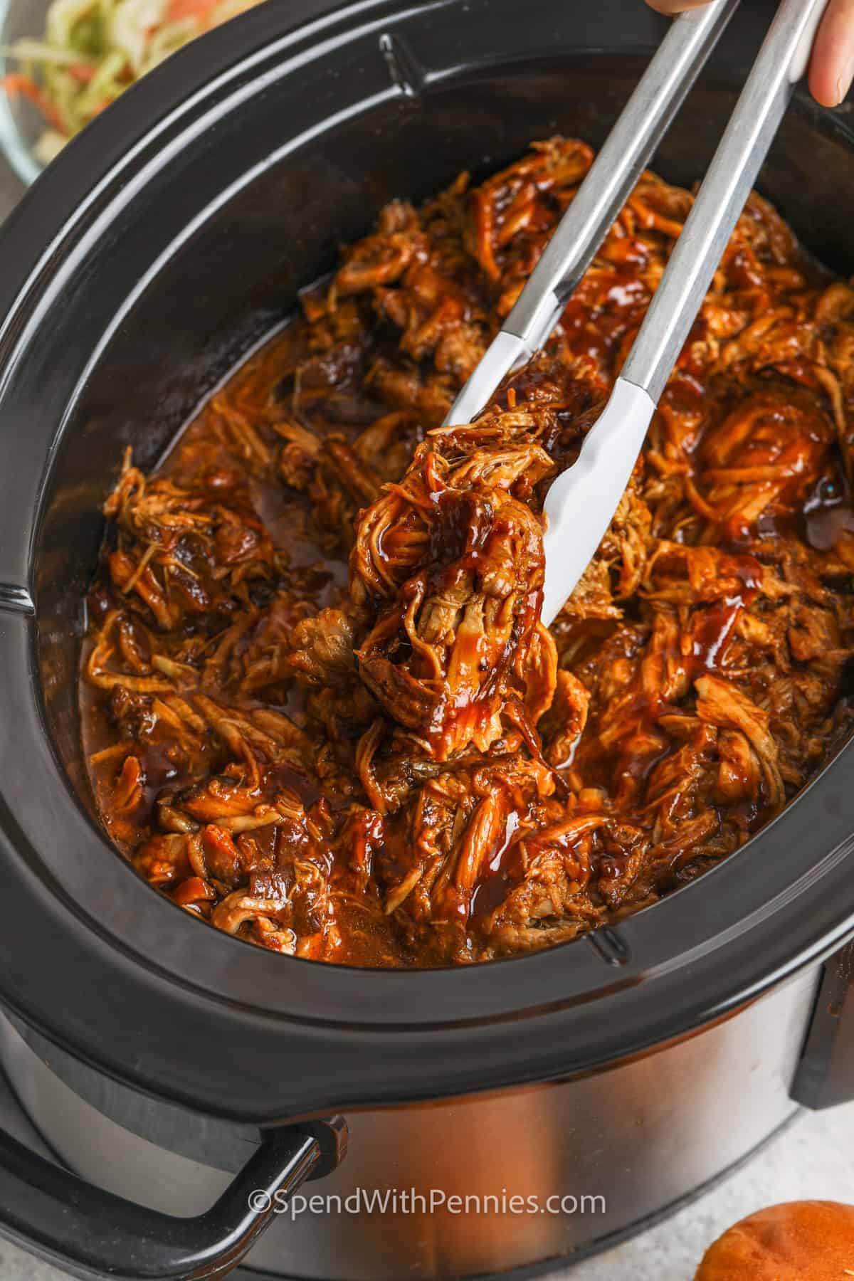 taking pork out of the crockpot to make Slow Cooker Pulled Pork Sandwiches