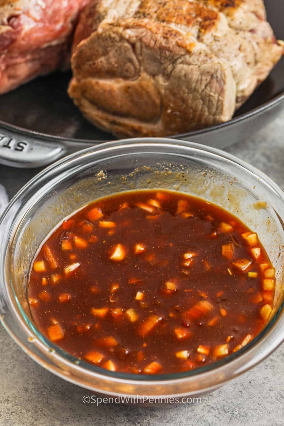 sauce with pork cooking in a pan to show how to make Slow Cooker Pulled Pork Sandwiches