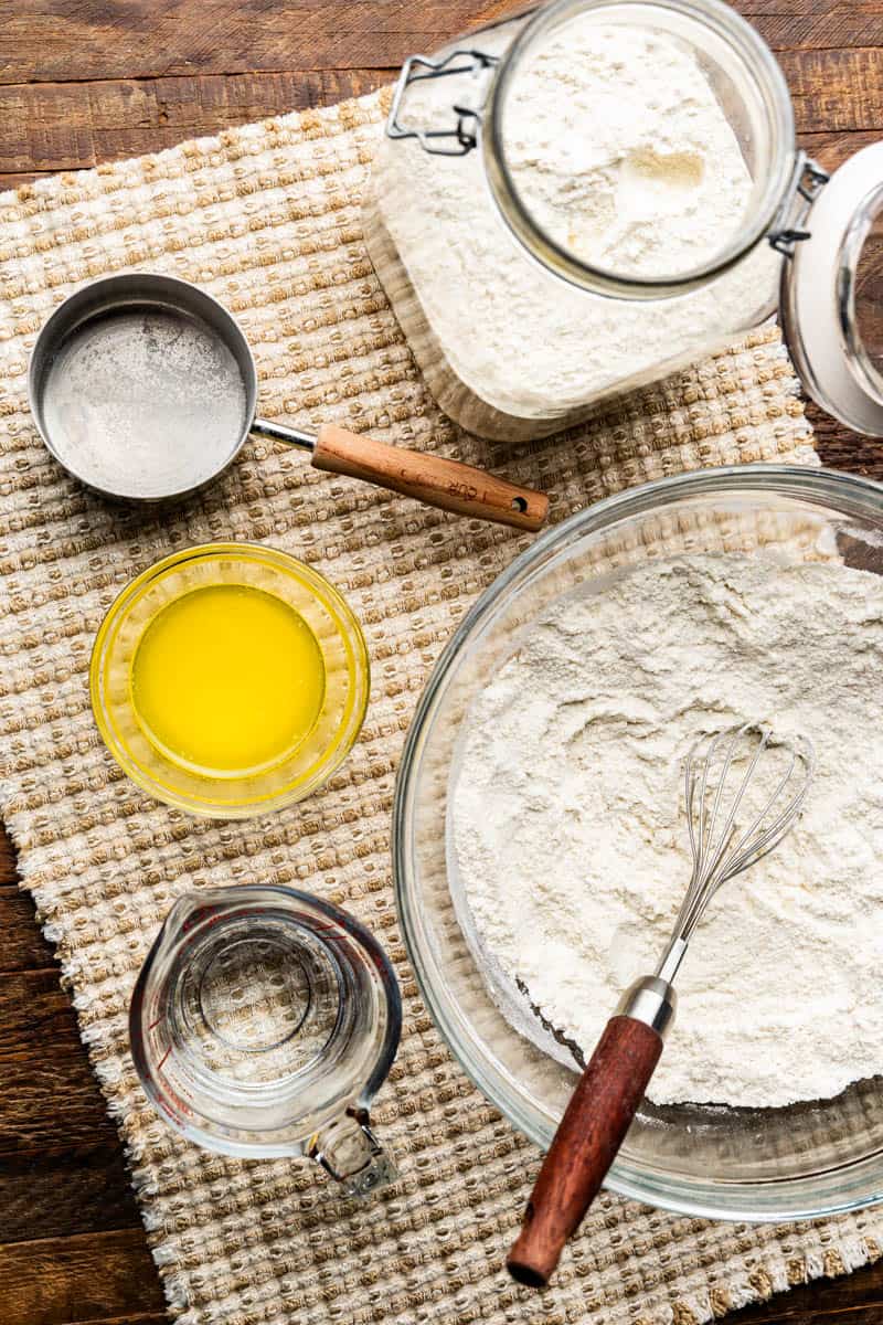 An overhead view of a jar of waffle mix with a bowl of it being prepared.