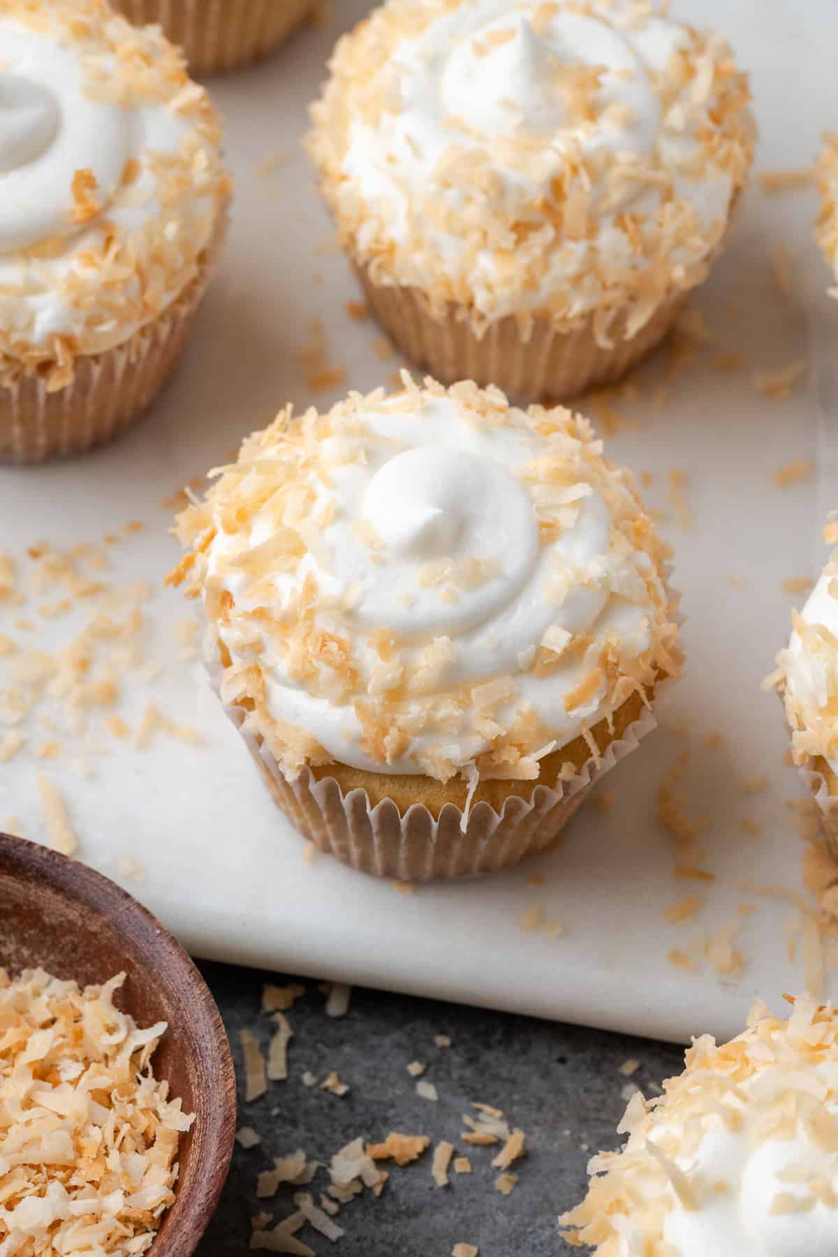 Almond cupcakes with swirls of coconut buttercream topped with toasted coconut.