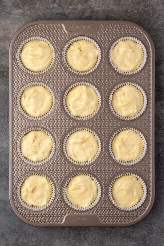 A 12-well muffin pan filled with cupcake batter.