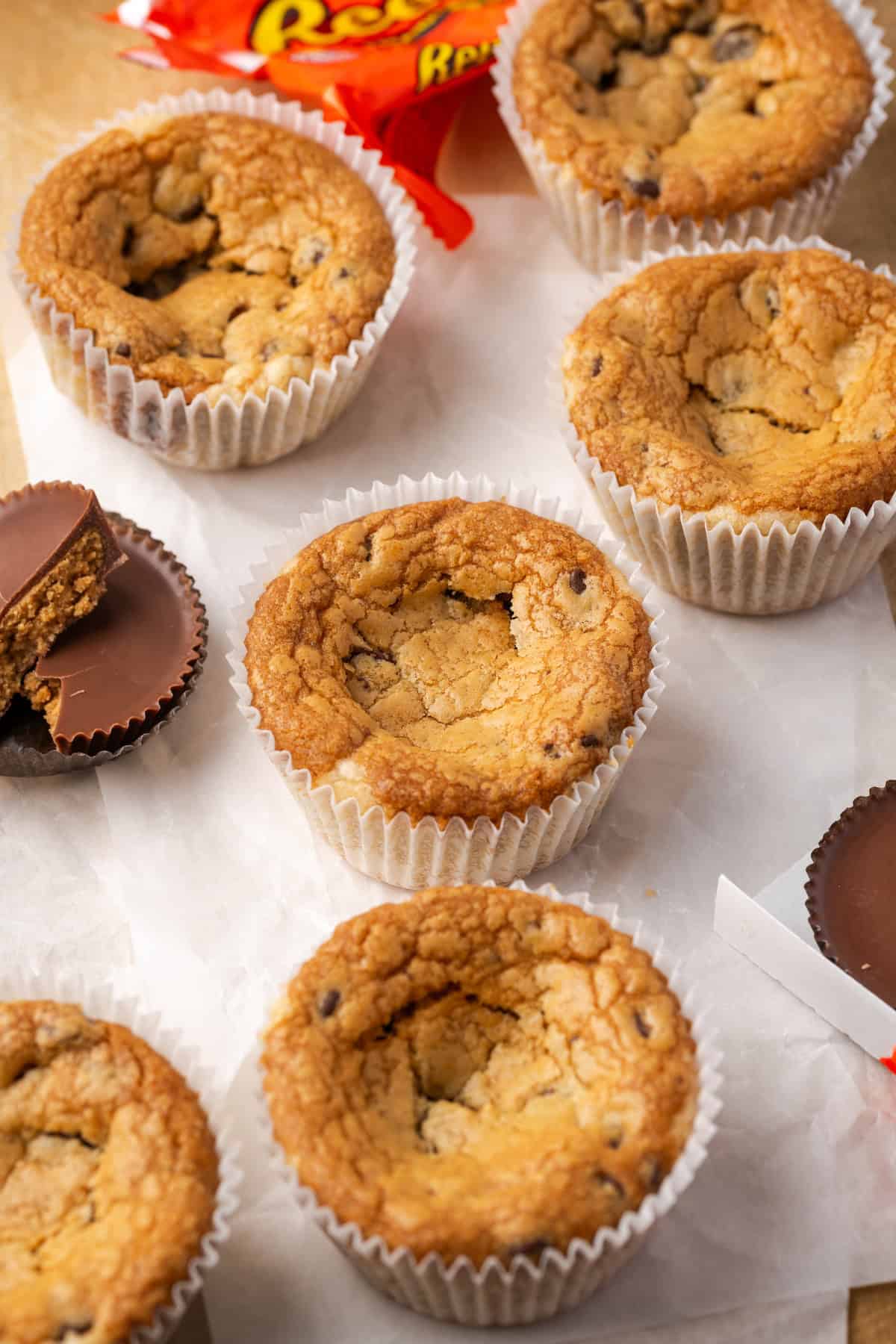 Cookie cups next to partially unwrapped Reese's peanut butter cups.