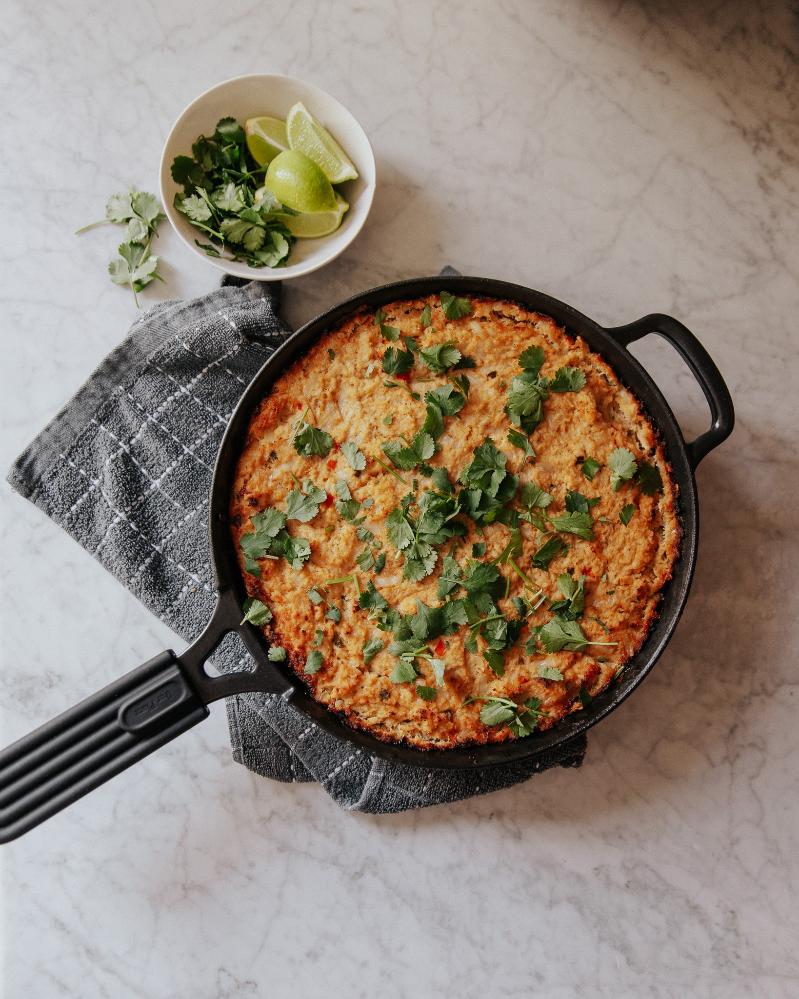 A cast iron skillet filled with hot chipotle chicken dip topped with cilantro