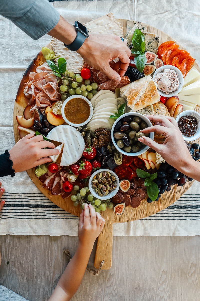 A charcuterie board filled with olives, figs, cheeses, salami, crackers, breads and spreads