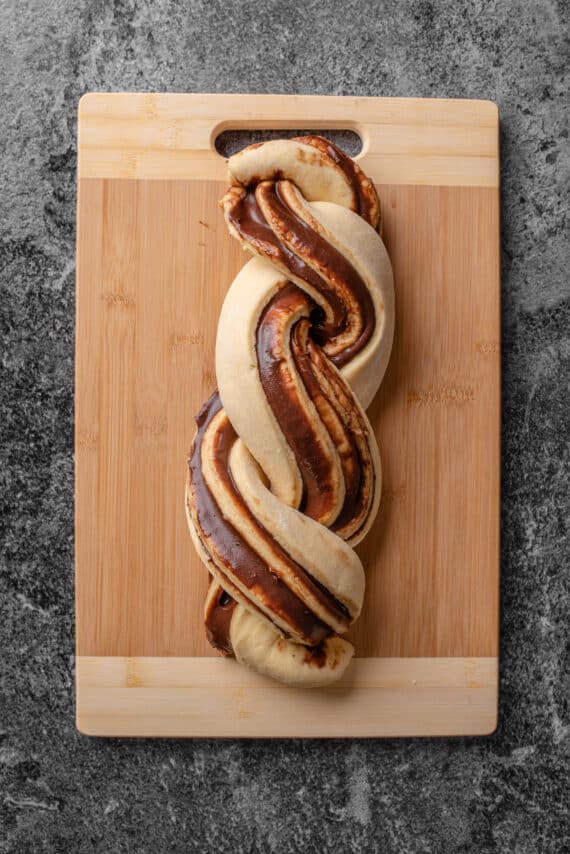 Twisted chocolate babka dough on a wooden cutting board.