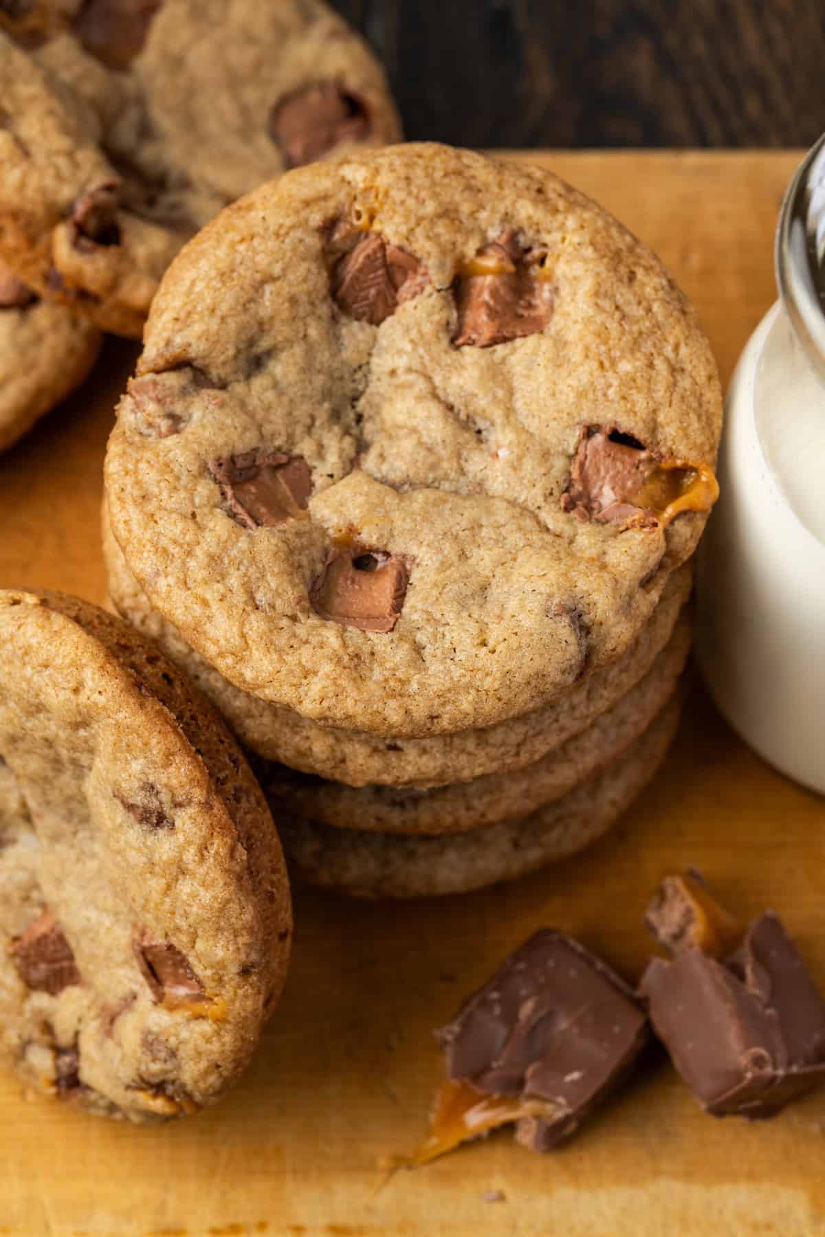 Overhead view of a stack of Milky Way cookies next to chopped Milky Way candy bars and a jug of milk.