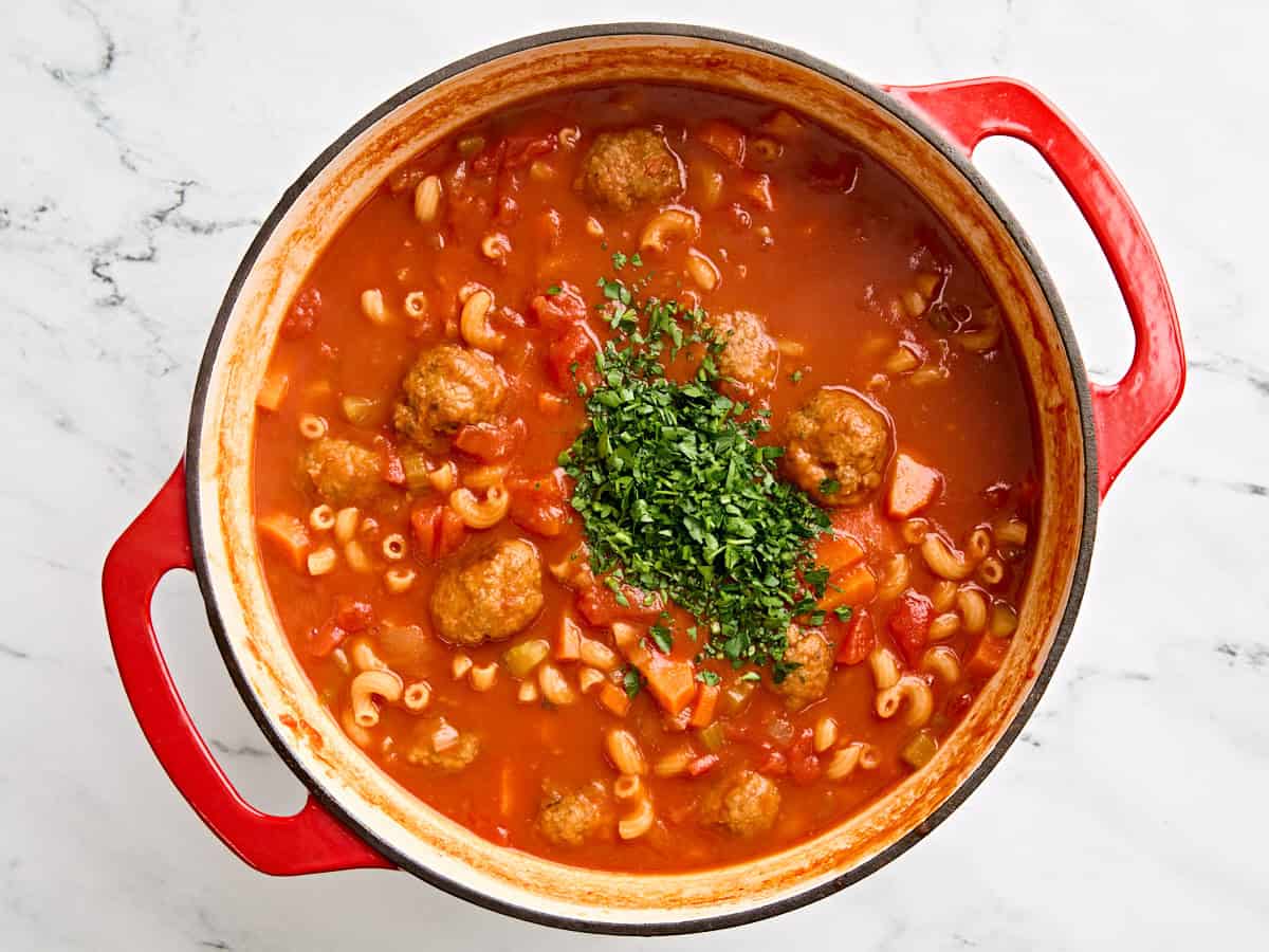 Chopped fresh parsley added to a pot of hearty meatball soup.
